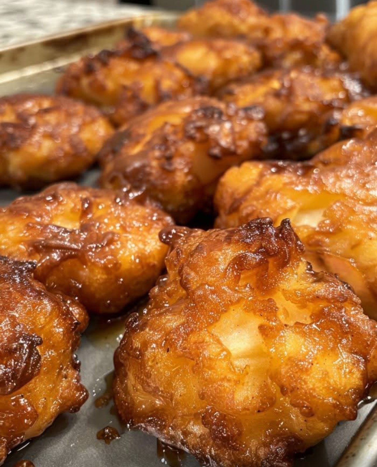 Golden baked apple fritters drizzled with vanilla glaze on a plate