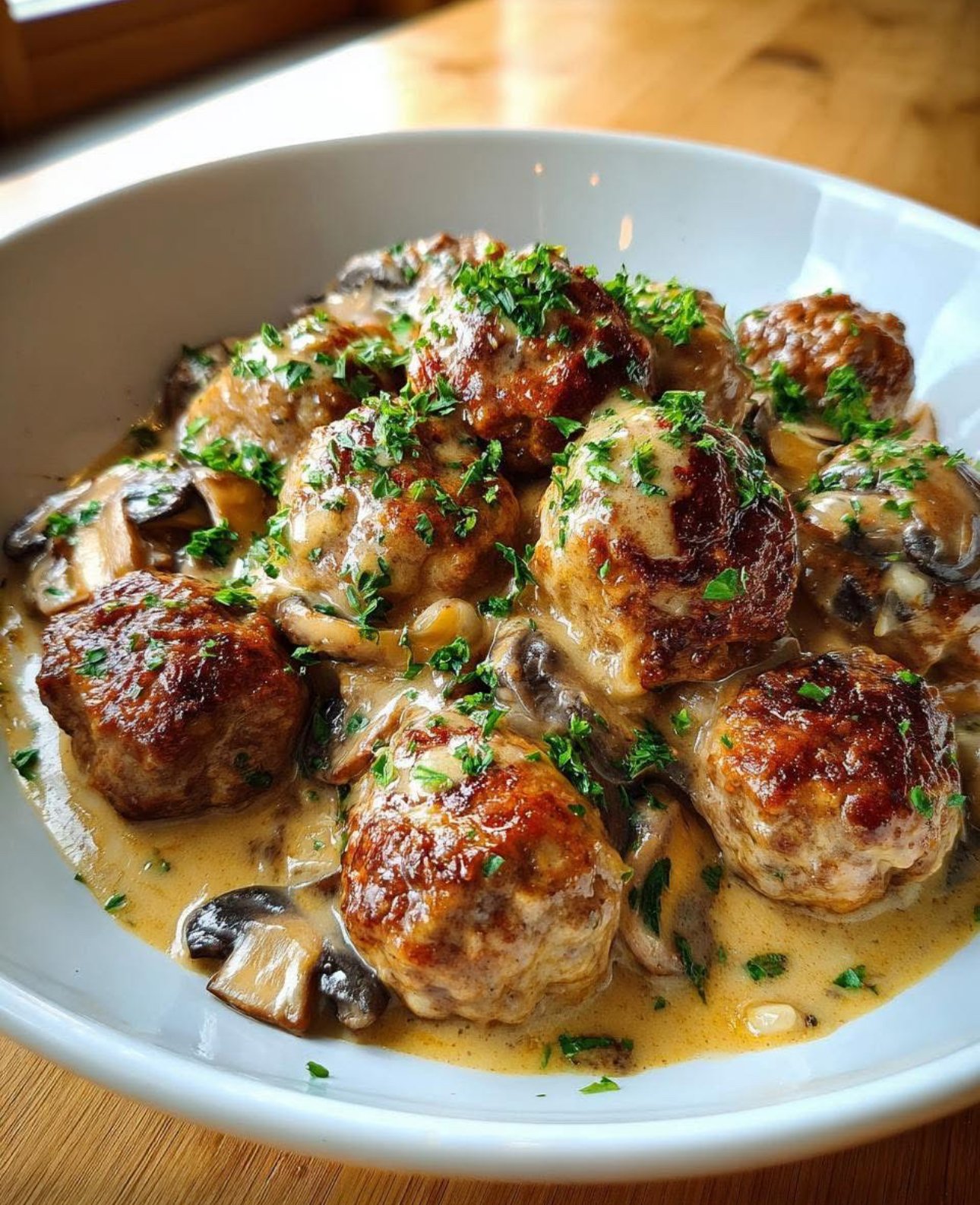 Homemade meatball stroganoff served over egg noodles with creamy mushroom sauce and parsley garnish