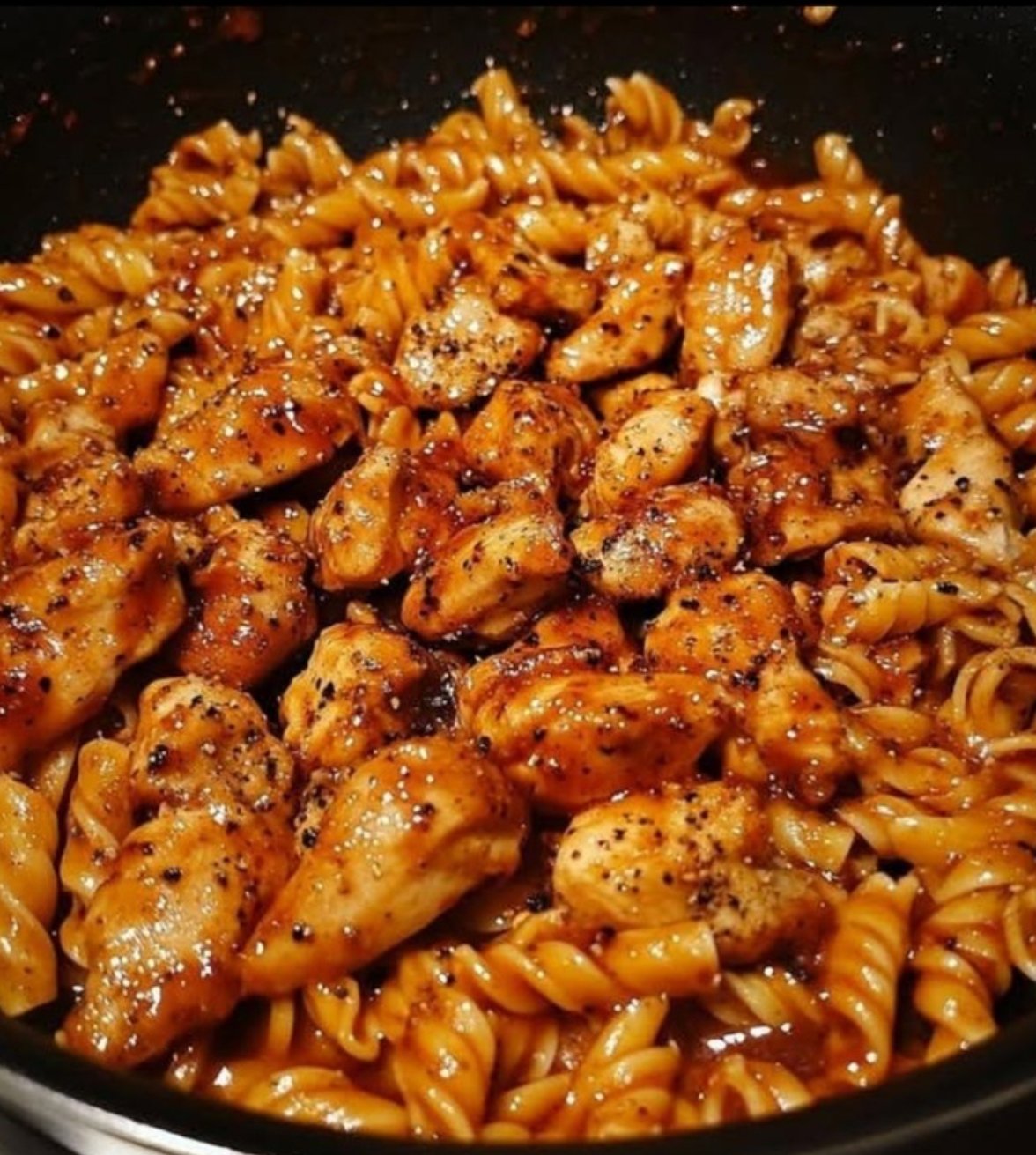 Creamy one-pot honey garlic BBQ chicken pasta in a skillet topped with parsley