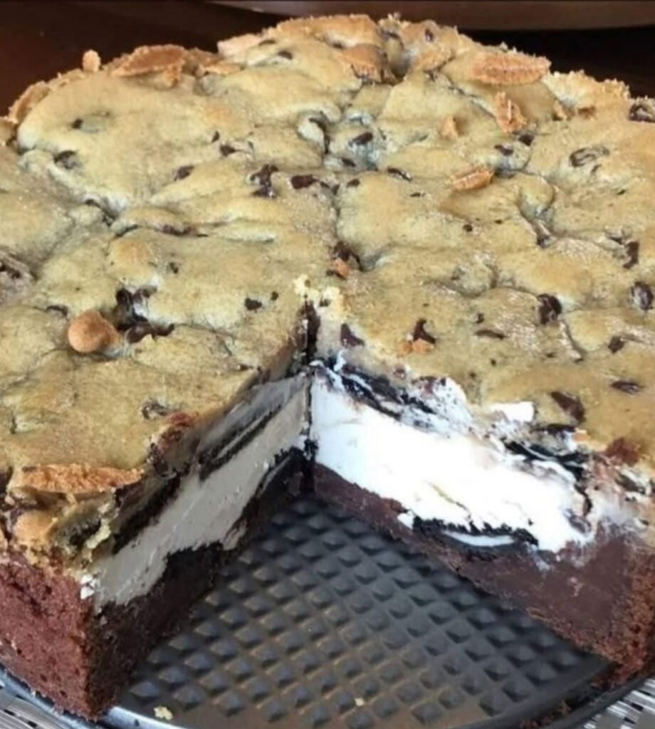 Close-up of 5 Layer Cookie Box Brownie Cheesecake with whipped cream topping on a serving plate