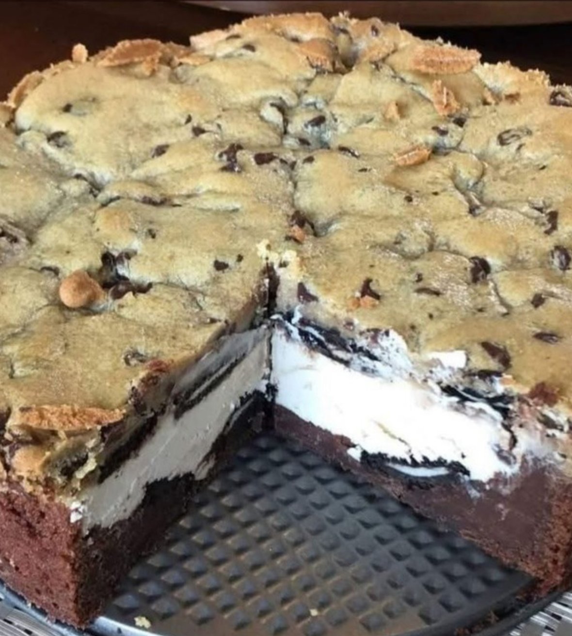 Close-up of 5 Layer Cookie Box Brownie Cheesecake with whipped cream topping on a serving plate