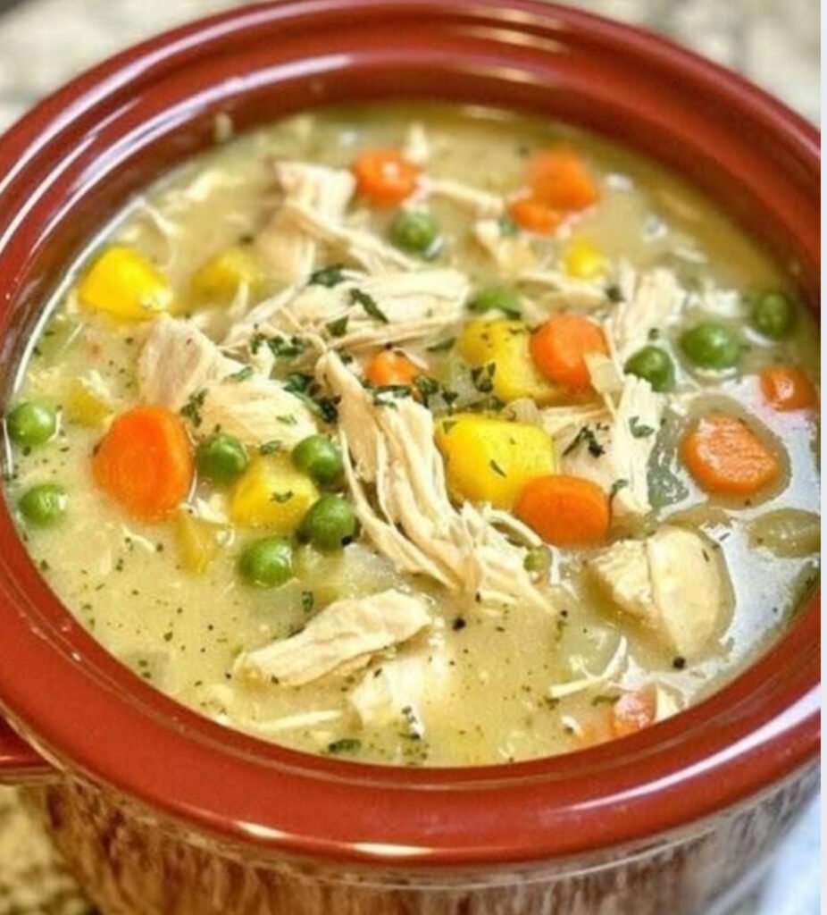 Creamy chicken soup in a white bowl garnished with fresh parsley.