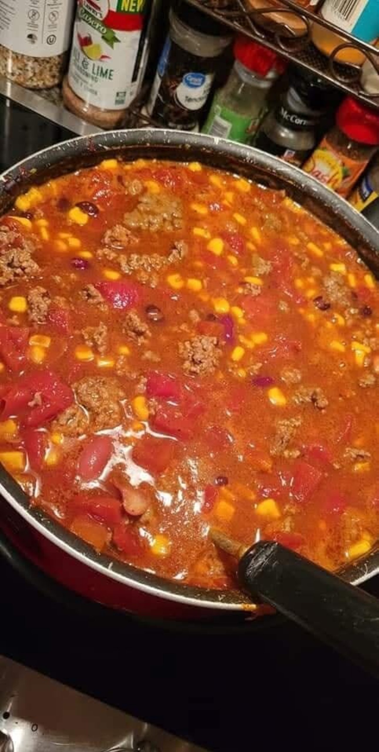 Bowl of slow cooker hearty taco soup with beans, corn, beef, and tomatoes, garnished with cheese and tortilla chips.