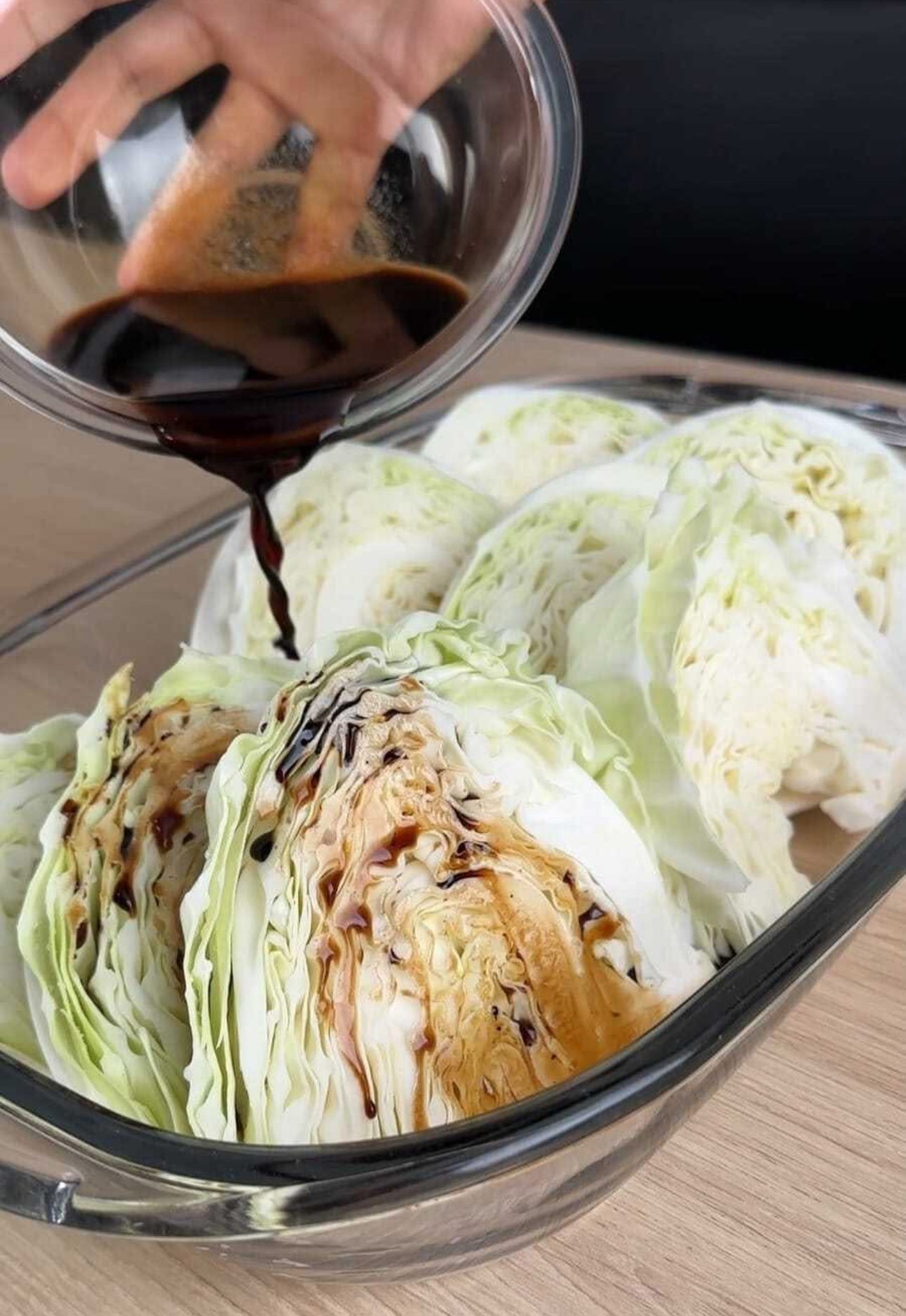 Crispy baked cabbage wedges drizzled with balsamic glaze and sprinkled with Parmesan cheese on a white plate.