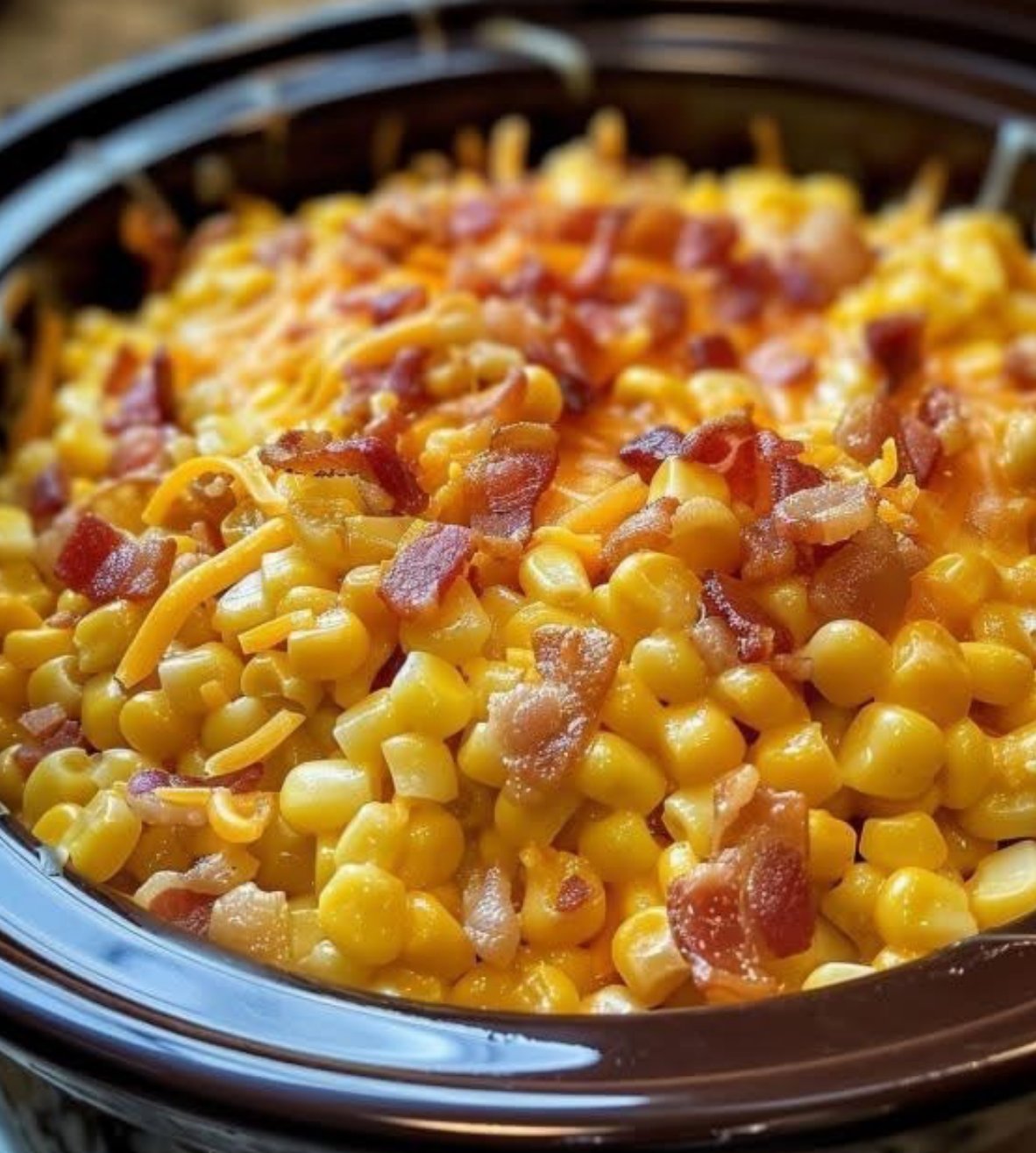 Slow Cooker Creamy Cheddar Corn with melted cheese, crispy bacon, and parsley served in a bowl.