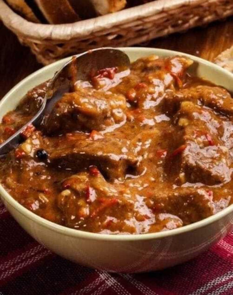 A bowl of old-fashioned beef stew with tender beef, potatoes, and carrots in rich broth, served with crusty bread.