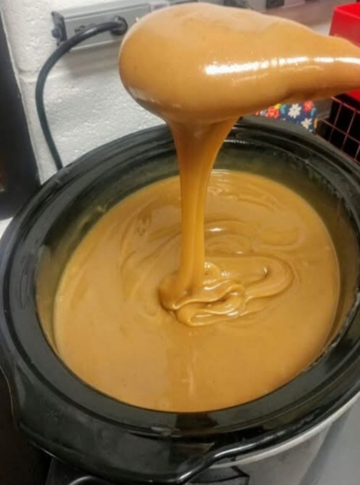 Rich and creamy homemade caramel sauce in a saucepan with a spoon.