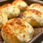 Golden low-carb cheese buns made with almond flour, mozzarella, and cream cheese on a parchment-lined tray