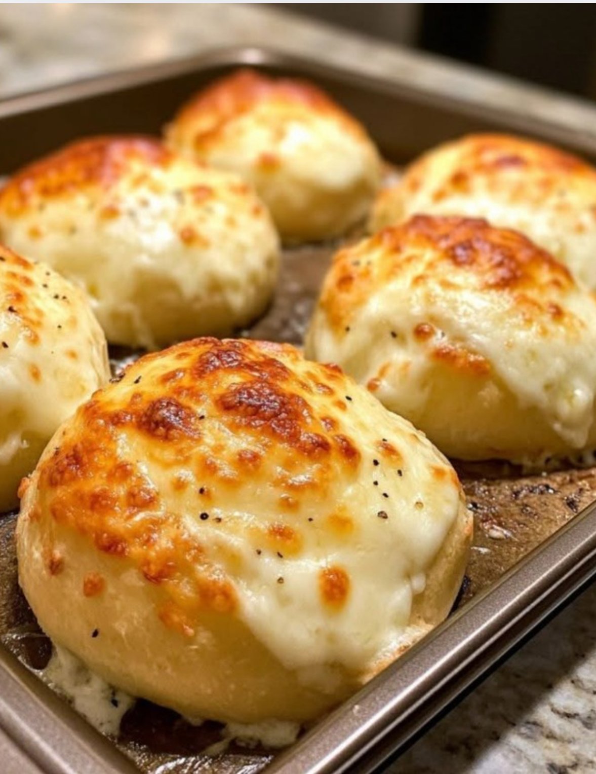 Golden low-carb cheese buns made with almond flour, mozzarella, and cream cheese on a parchment-lined tray